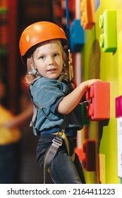 Happy School Boy In Red Helmet On Climbing Class At Indoor Climbing And Bouldering Centre. Kid Boy Smiling To The Camera And Keeping Thumb Up