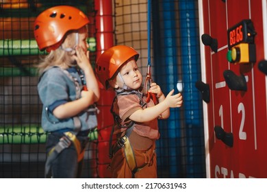 Happy School Boys In Red Helmets On Climbing Class At Indoor Climbing And Bouldering Centre. Kids Boys At Indoor Climbing Class For Kids