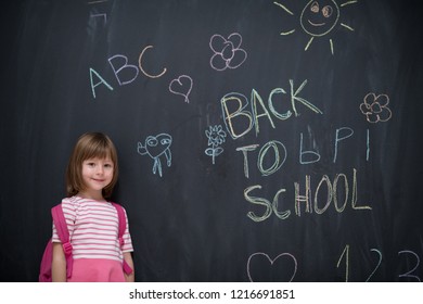 Happy School Girl Kind mit Rucksack, der zurück zur Schule auf schwarzer Tafel schreibt