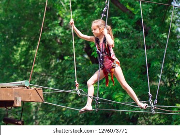 Happy School Girl Enjoying Activity In A Climbing Adventure Park On A Summer Day