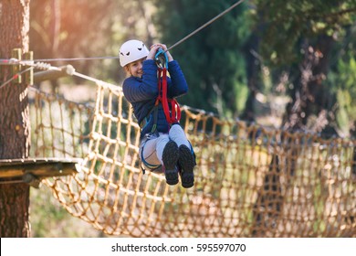 Happy school girl enjoying activity in a climbing adventure park on a summer day - Powered by Shutterstock