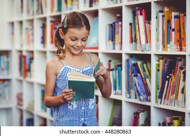 Happy School Girl Reading A Book In Library At School