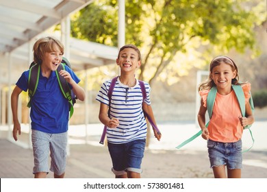 Happy School Kids Running In Corridor At School