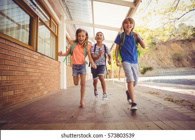 Happy School Kids Running In Corridor At School