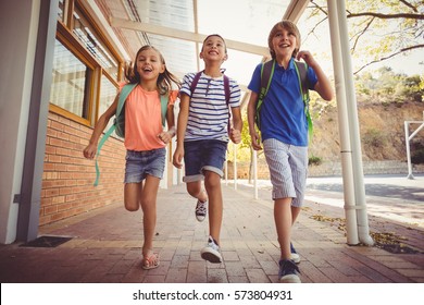Happy School Kids Running In Corridor At School