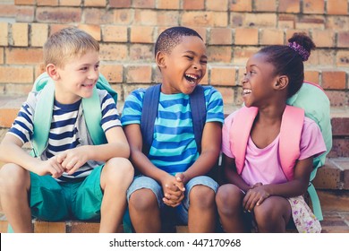Happy school kids sitting together on staircase at school