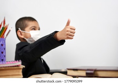 Happy Schoolboy In Face Mask. Mixed-race Kid Shows Thumbs-up Gesture Between Pile Of Books. Back To School After Covid-19. School Year Start After Long Delay Due To Coronavirus