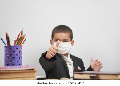 Happy Schoolboy In Face Mask. Mixed-race Kid Shows Thumbs-up Gesture Between Pile Of Books. Back To School After Covid-19. School Year Start After Long Delay Due To Coronavirus