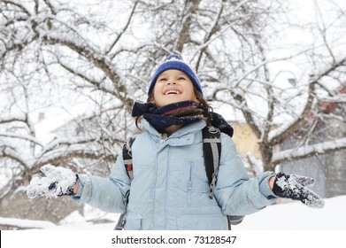 Happy Schoolboy Kid Wearing Warm Clothes In Snow On A Cold Winter Day, Smiling And Joying