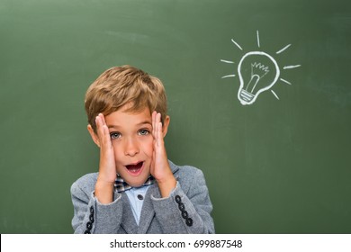 happy schoolboy next to chalkboard with lightbulb sign - Shutterstock ID 699887548
