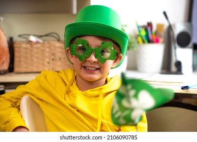 Happy Schoolboy On St. Patrick's Day. Wearing A Green Hat, Wearing Green Clover-shaped Glasses, Waving A Small Green Flag. Inside