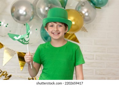 Happy Schoolboy On St. Patrick's Day. Wearing A Green Hat, Waving A Small Green Flag