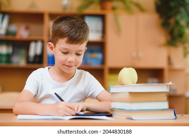 Happy schoolboy sitting at desk, classroom - Shutterstock ID 2044830188