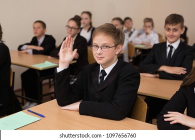Happy schoolchildren sit at a desk in the classroom
