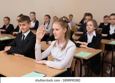 Happy schoolchildren sit at a desk in the classroom