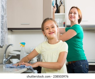 Happy Schoolgirl Helping Mother Dusting Furniture Indoor. Focus On Girl