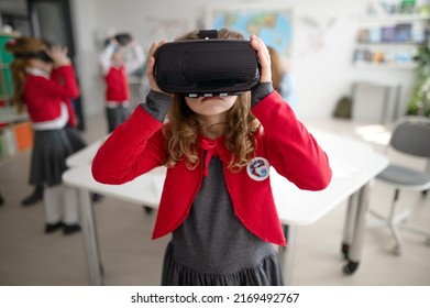 Happy schoolgirl wearing virtual reality goggles at school in computer science class