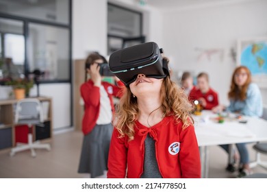 Happy schoolgirl wearing virtual reality goggles at school in computer science class