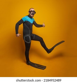 Happy scuba diver diving man going to the side against bright orange studio wall background - Shutterstock ID 2184952489
