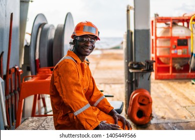 Happy Seaman AB Or Bosun On Deck Of Vessel Or Ship , Wearing PPE Personal Protective Equipment - Helmet, Coverall, Lifejacket, Goggles. Safety At Sea