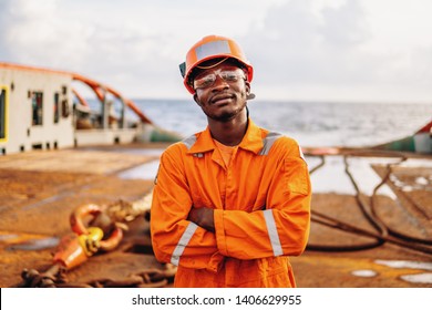 Happy Seaman AB Or Bosun On Deck Of Vessel Or Ship , Wearing PPE Personal Protective Equipment - Helmet, Coverall, Lifejacket, Goggles. Safety At Sea