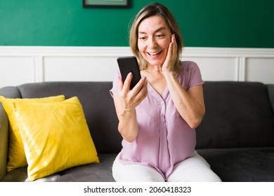 I'm So Happy To See You. Surprised Mature Woman Holding Her Smartphone While Receiving A Video Call From Her Family Or Friends 