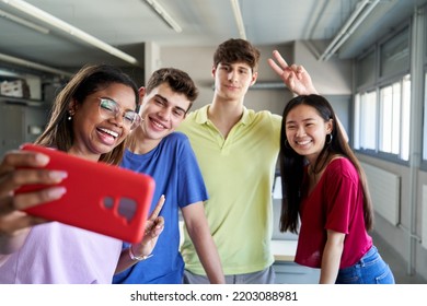 Happy Selfie Of Four Student Friends Back To School, Reunion After Summer Holidays. Multicultural Group Of Young People Meet Again At Classroom. Smiling And Doing The Peace Sign, Using Phone.