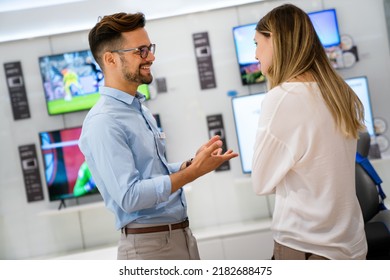 Happy Seller Man Helping To Woman To Buy A New Digital Smart Device In Tech Store.