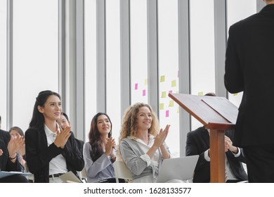 Happy Seminar Concept. Group Of Diversity Business Audience Are Enjoy Listening To Male Speaker And Clapping For Him With Smiling Faces At Conference Room Background.