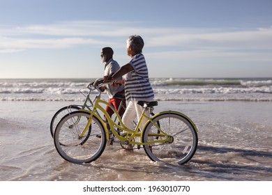 Happy senior african american couple with bicycles walking together on the beach. travel vacation retirement lifestyle concept - Powered by Shutterstock