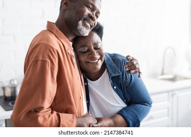 happy and senior african american couple holding hands and hugging at home - Shutterstock ID 2147384741