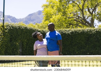 Happy senior african american couple with tennis rackets embracing on sunny grass tennis court. Senior lifestyle, retirement, sport, summer, fitness, hobbies and leisure activities. - Powered by Shutterstock
