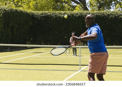 Happy senior african american couple playing tennis on sunny grass tennis court. Senior lifestyle, retirement, sport, summer, fitness, hobbies and leisure activities. - Powered by Shutterstock