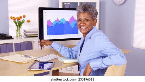 Happy senior african businesswoman sitting at desk