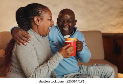 Happy senior african couple having fun drinking hot chocolate together at home - Powered by Shutterstock