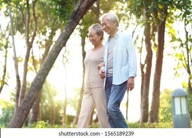 Happy Senior Asian Couple Walking Talking Relaxing Outdoors In Park