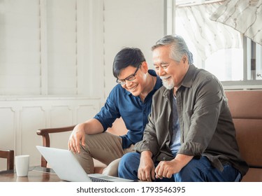 Happy Senior Asian Father And Adult Son Using Laptop Talking On Video Call In Living Room