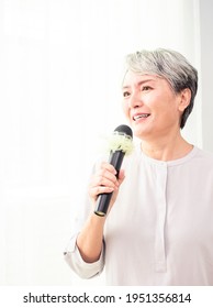 Happy Senior Asian Woman Singing With Microphone.