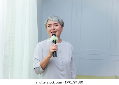 Happy Senior Asian Woman Singing With Microphone.