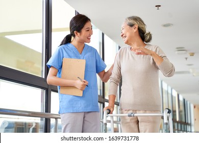 Happy Senior Asian Woman Talking To Physical Therapist In Rehab Center