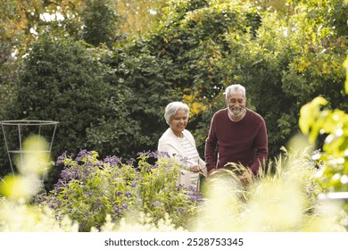 Happy senior biracial couple holding hands and looking at plants in garden at home, copy space. Senior lifestyle, retirement, nature and domestic life, unaltered. - Powered by Shutterstock