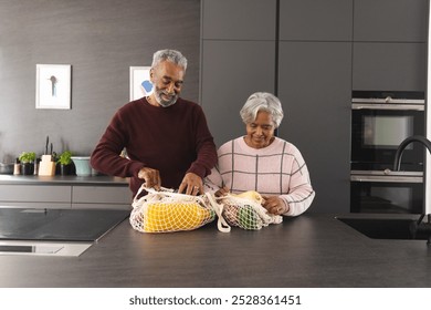 Happy senior biracial couple unpacking bags of vegetables in kitchen at home. Senior lifestyle, retirement, food, shopping and domestic life, unaltered. - Powered by Shutterstock