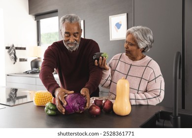 Happy senior biracial couple unpacking bags of vegetables in kitchen at home. Senior lifestyle, retirement, food, shopping and domestic life, unaltered. - Powered by Shutterstock