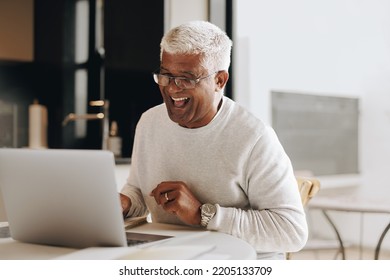 Happy senior businessman laughing cheerfully during a virtual meeting in his home office. Mature businessman having a video conference with his colleagues while working from home. - Powered by Shutterstock