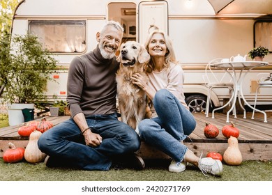 Happy senior caucasian couple spouses travelers explorers sitting in the garden near camper van trailer with their dog pet golden retriever with vegetables on the porch - Powered by Shutterstock