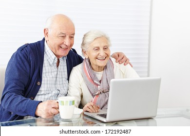 Happy Senior Citizen Couple Using Laptop Computer At Home