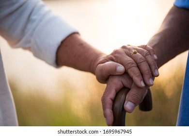 A happy senior couple asian old man and woman hold hand each other and standing in summer near mountain and lake during sunrise or sunset . Senior healthcare and relationship concept.