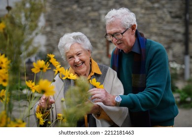 Happy Senior Couple At Autumn City Walk, Posing With Flowers.