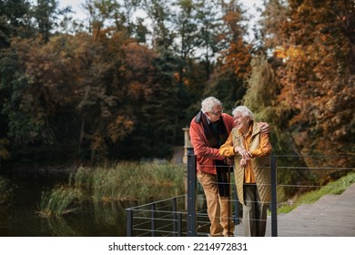 Happy Senior Couple At Autumn Walk Near The Lake, Having Break.