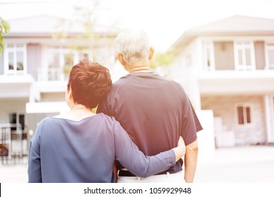 Happy Senior Couple From Behind Looking At Front Of House And Car. Warm Tone With Sunlight